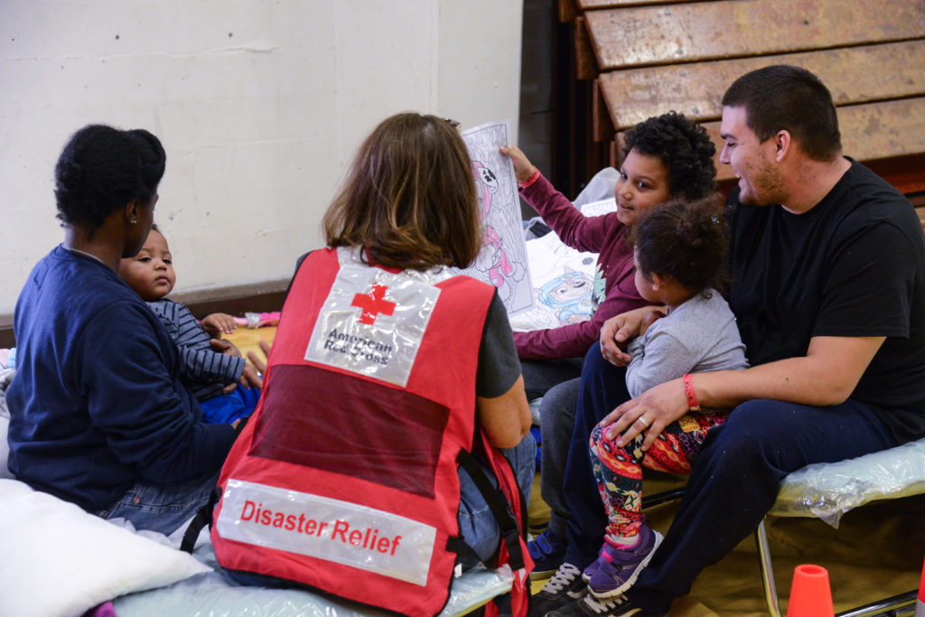 The Murillo family playing and talking with a Red Cross volunteer in a shelter. 