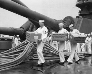 A44869Philadelphia, PA, July 1941 – On a combat ship three Navy pharmacists carry aboard a consignment of American Red Cross dried blood plasma for use by the Navy during World War II.
