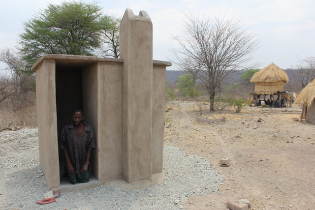 Tuesday Mwimba in front of his newly constructed Blair Toilet. Having a toilet on his homestead helps him avoid the dangers associated with going to the bush at night. 