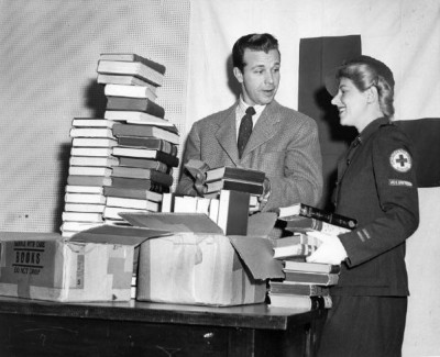 1943. Los Angeles, California. Radio and screen star Dick Powell autographing and packing away books he gave to the Red Cross for servicemen with the aid of Red Cross Volunteer Inez Asher. The books represent but a fraction of hundreds of volumes the star has given away to service libraries since the US government first appealed for book donations. Powell has visited many coast military outposts to make the presentations in person. 