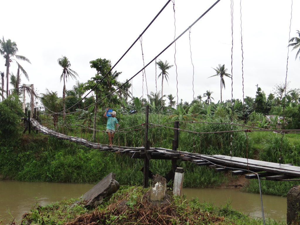A man traverses a bridge into his village in the Philippines