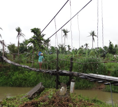 A man traverses a bridge into his village in the Philippines