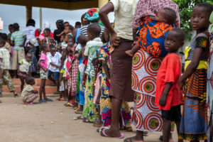 Mothers and children wait in line to be vaccinated in Cotonou, Benin after being informed of the campaign by Red Cross house-to-house mobilizers. American Red Cross/Javier Acebal.