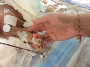Father hold's son Aaron's hand as he receives blood