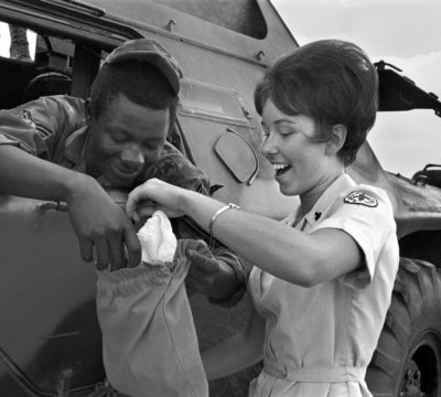 Red Cross Donut Dolly and soldier in Vietnam investigate the contents of his ditty bag. Sgt. Micka was on guard along the Tan Son Nhut air base perimeter in an armored personnel carrier.