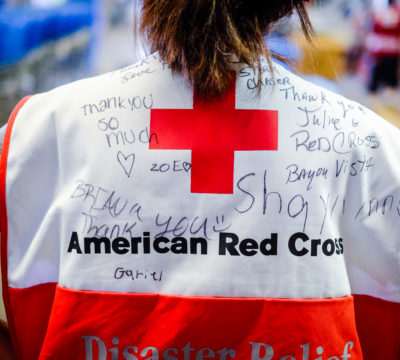 Red Cross volunteer Julie on her first deployment working with Distribution of Emergency Supplies Group shows off the back of her Red Cross vest that children signed with messages thanking the Red Cross for helping their families recover from Hurricane Harvey.