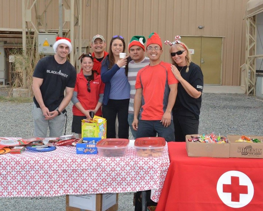 Volunteers stand in front of table full of treats during the Christmas holiday. 