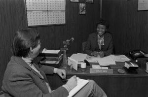 Shirley Hines talking to a colleague at her desk in D.C. 
