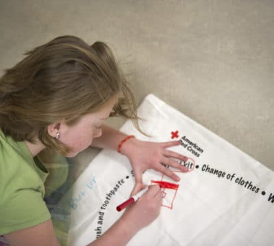 A student personalizes her pillowcase given by the Red Cross to store her emergency supplies in preparation for future weather emergencies.