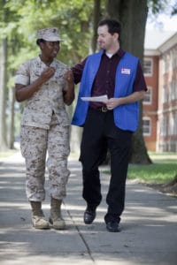 A Red Cross volunteer walking with a member of the military.