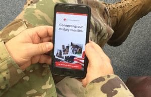 photo of a member of the military holding her phone, which has the hero care app pulled up.