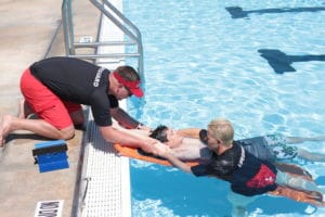 Lifeguards working on spinal back-boarding in a pool. 