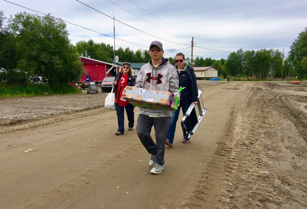 Three volunteers walking to distribute smoke alarms in Lower Kalskag.