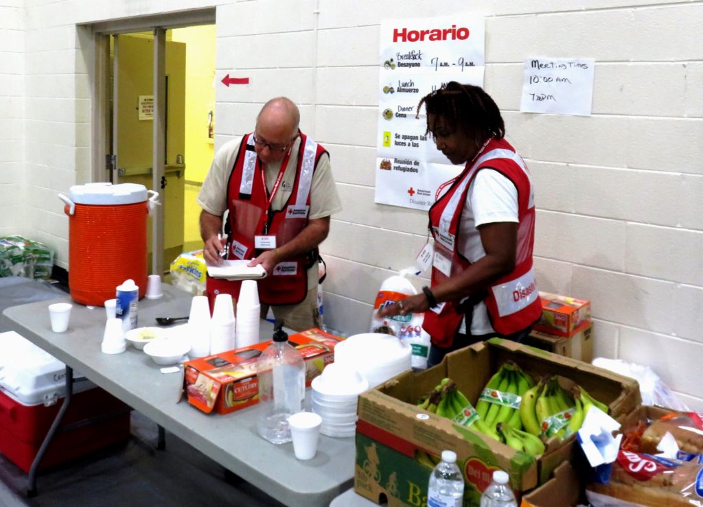 Shelter volunteers Paul "Paco" Garcia and Emma Tucker-Krug work to organize a meal table at a shelter in Columbia, South Carolina. 