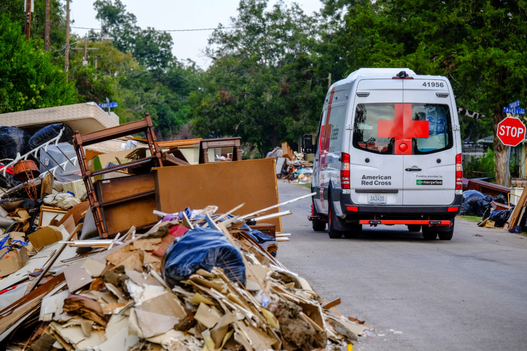 An emergency response vehicle riding through a neighborhood damaged by a disaster.