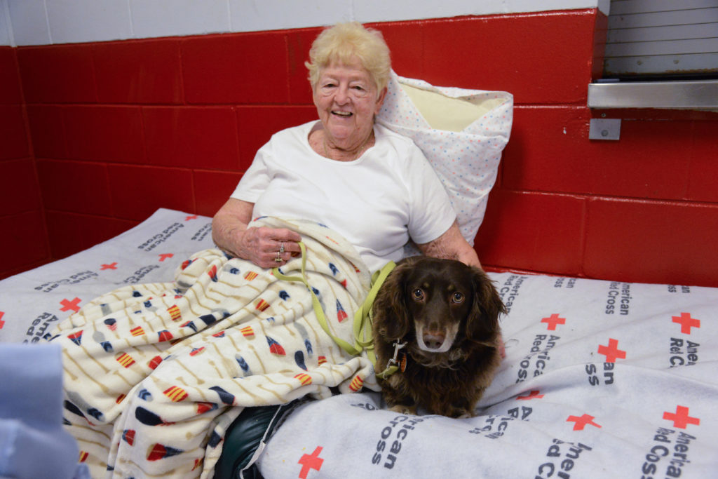 A shelter resident sitting on a bed with her dog. 