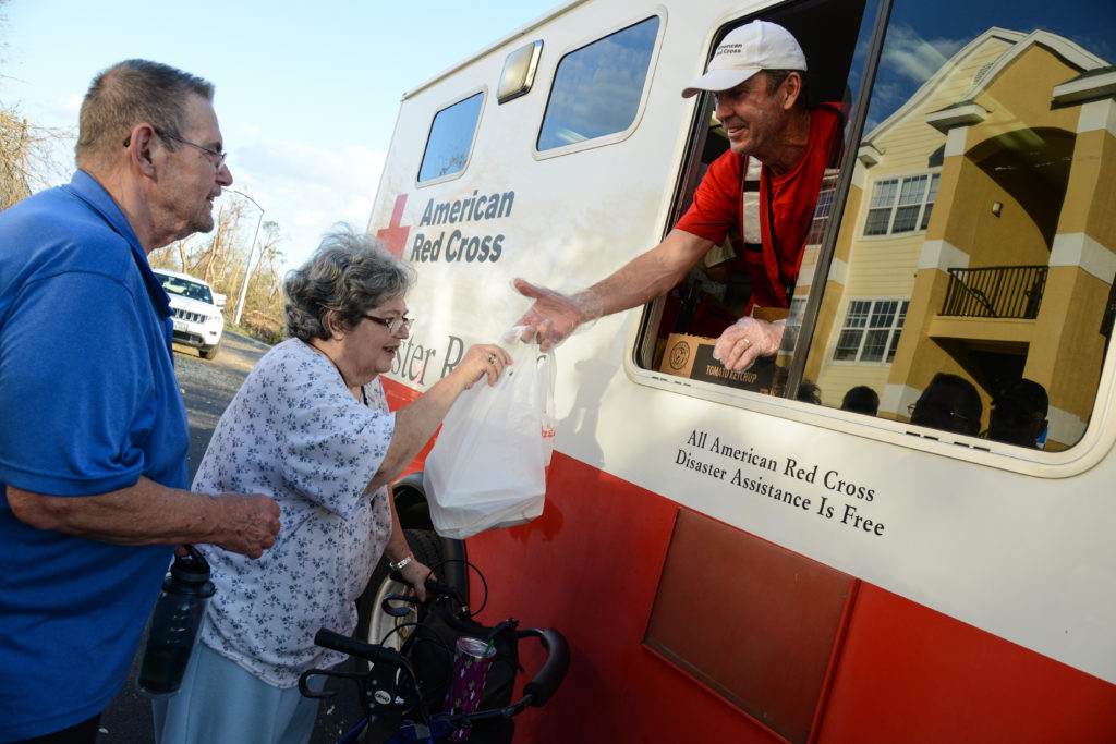 A woman and her husband stand outside of a Red Cross emergency vehicle to get a meal. 
