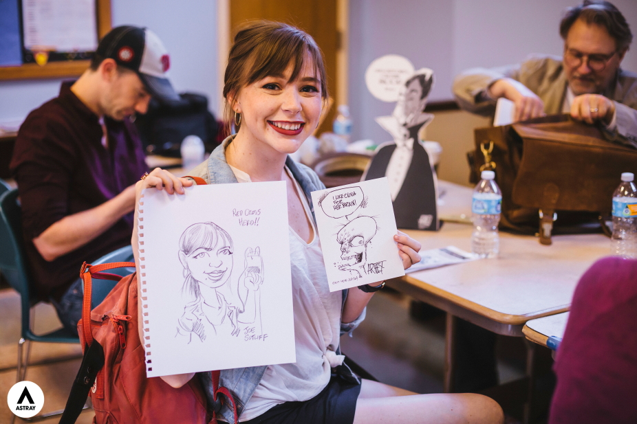 A cartoonist holding up one of her illustrations during a blood drive. 