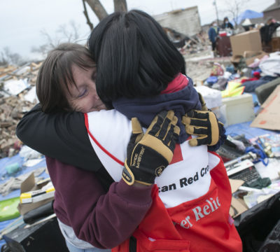 A Red Cross volunteer hugging a disaster victim.