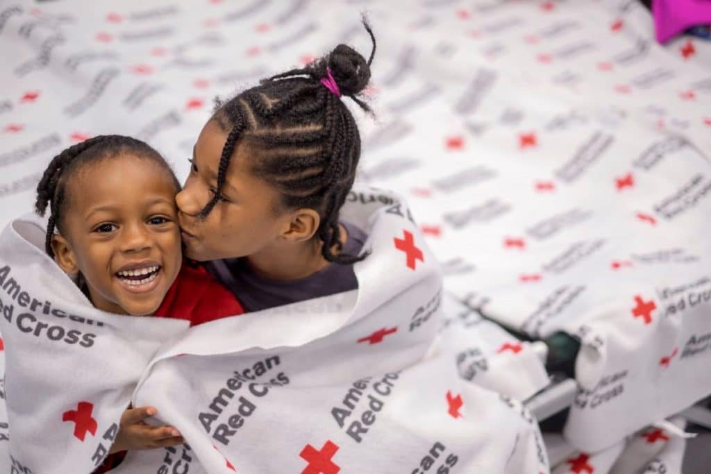 Jecek and her sister Charsidy wrapped in a Red Cross blanket at a shelter. 
