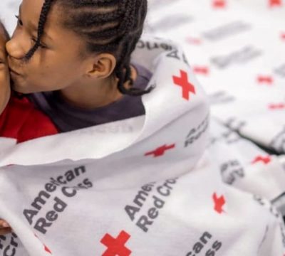 Jecek and her sister Charsidy wrapped in a Red Cross blanket at a shelter.