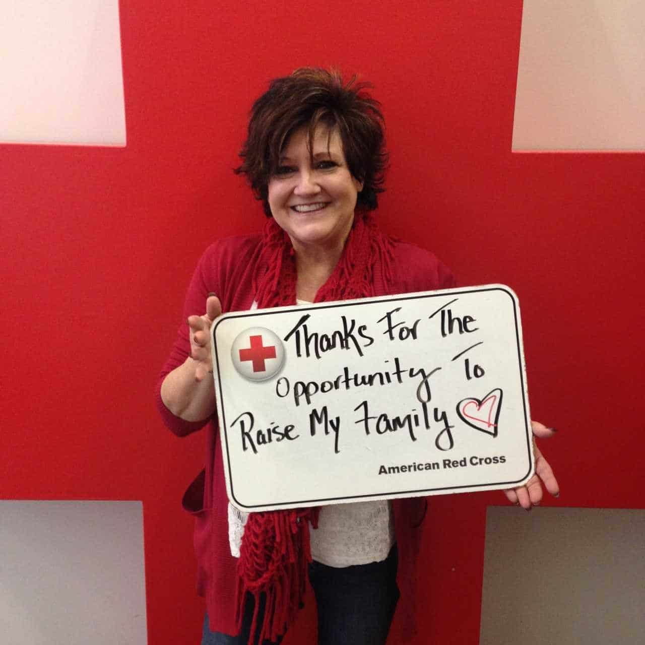 Sheri holding up a sign thanking blood donors for the opportunity to raise her family.