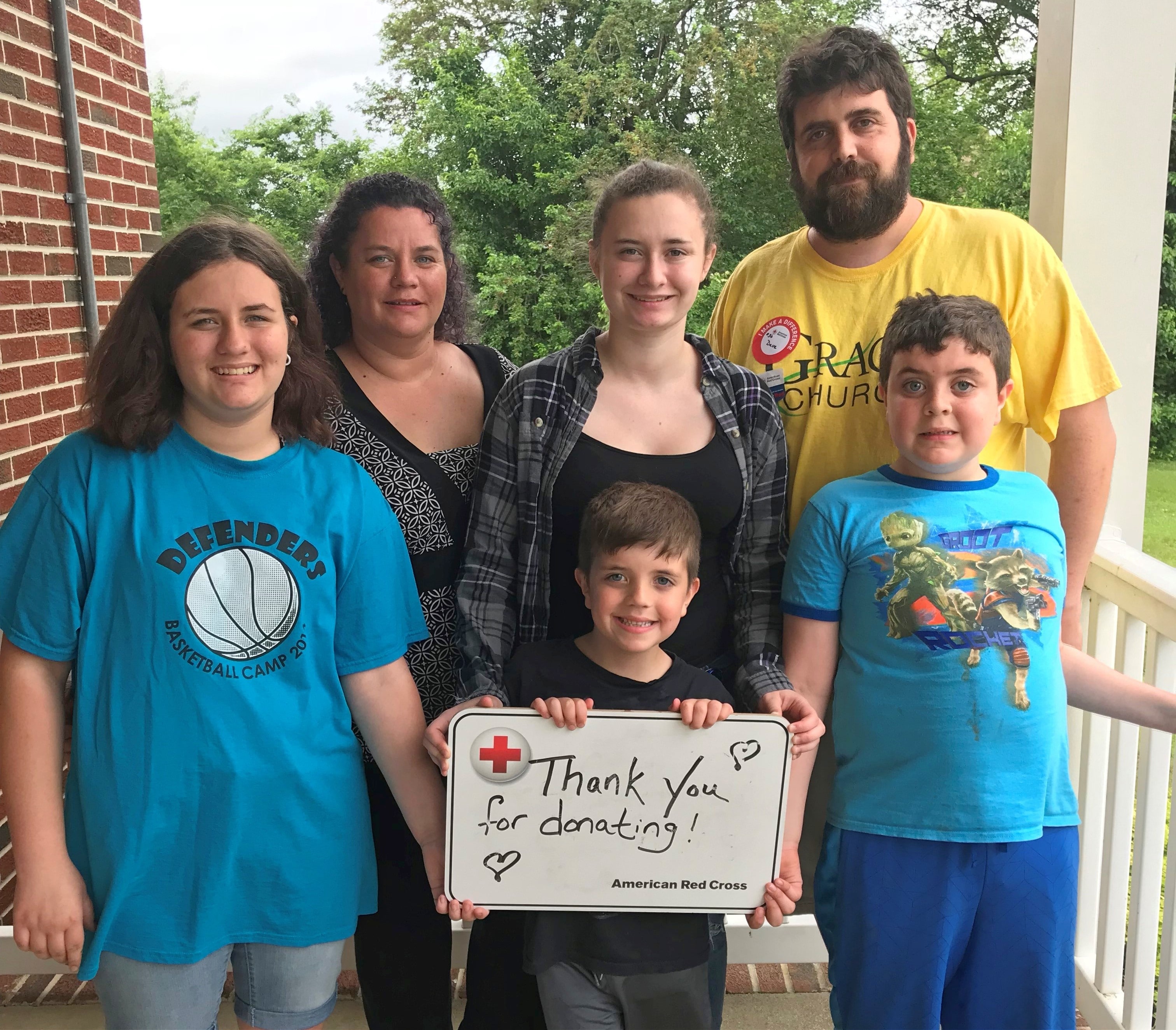 Jonathan and his family standing with a sign to thank blood donors. 