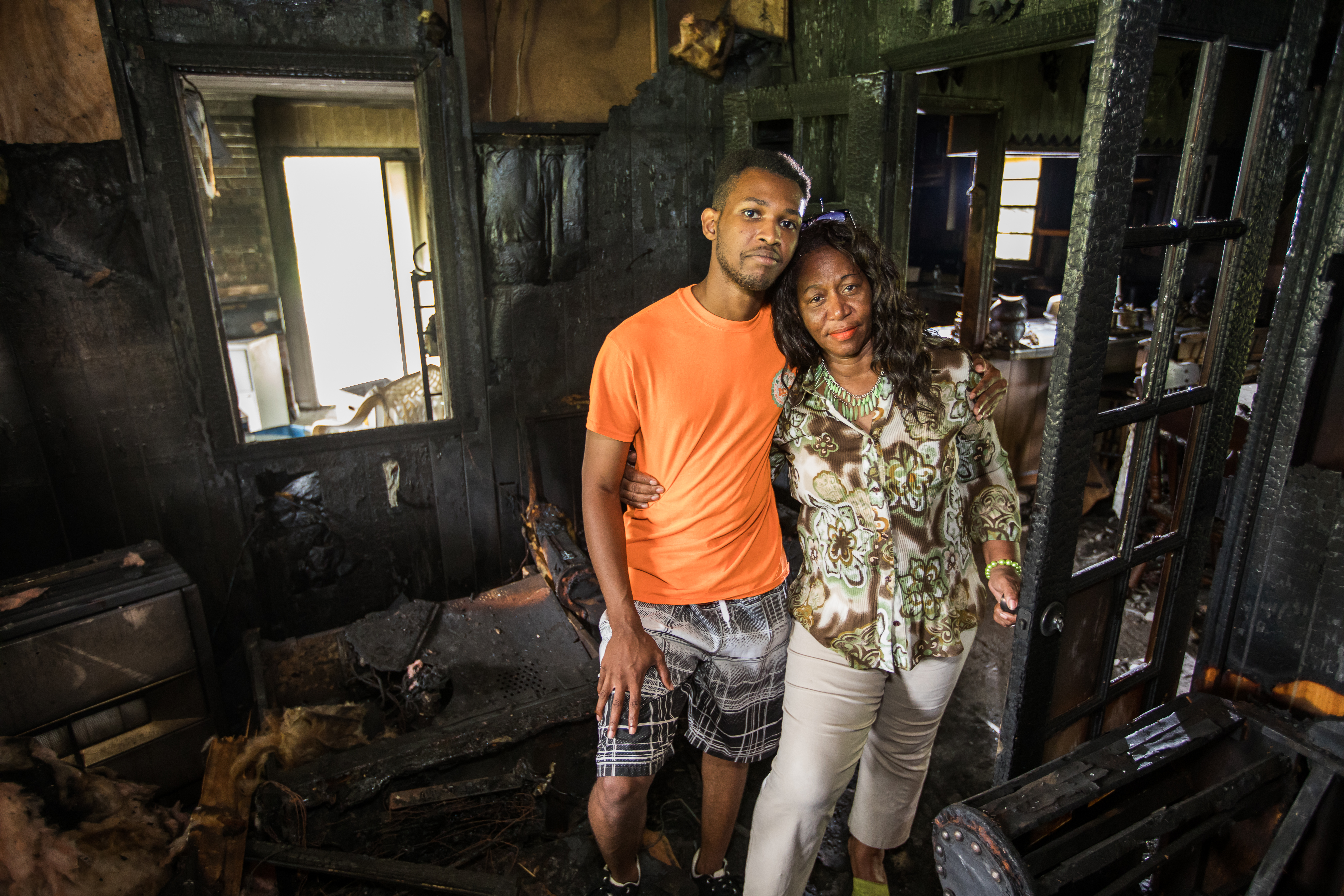 A mom and her son standing in their burned house after a home fire.