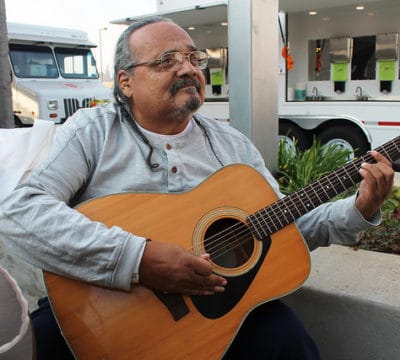 Joe Avila playing a guitar outside of a Red Cross shelter.