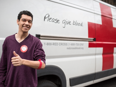 A blood donor standing in front of a blood mobile after giving his donation.