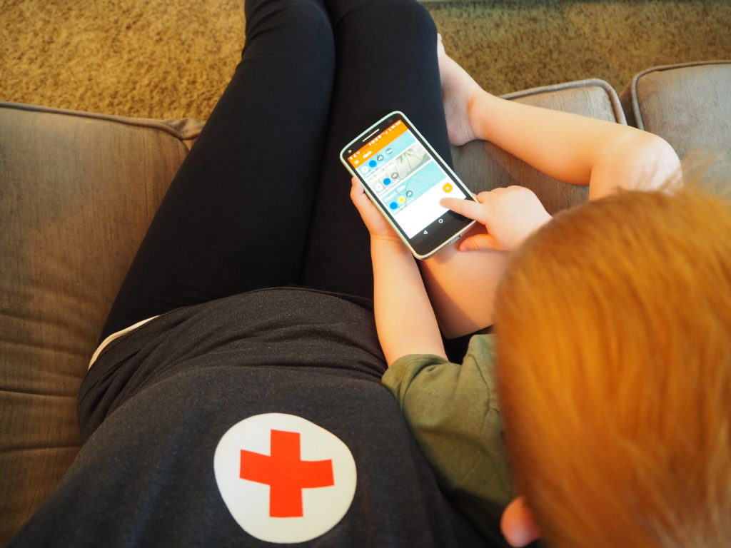 Sarah and her son scrolling through the Red Cross Emergency App. 