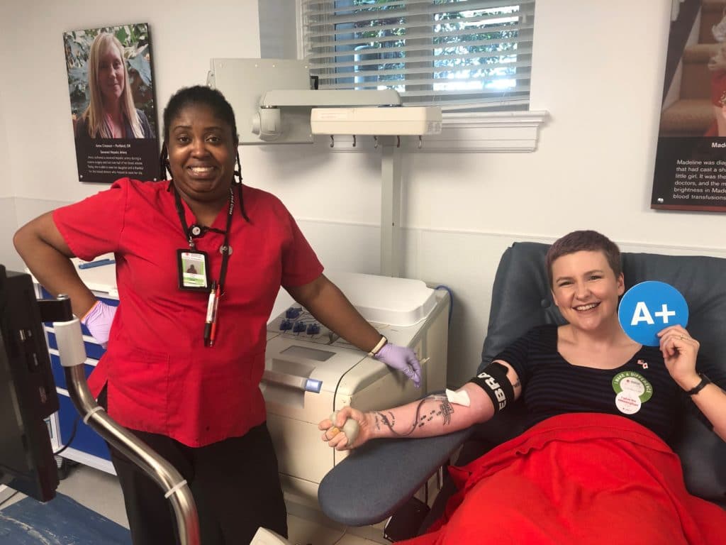 Sam standing with her phlebotomist during a blood donation.