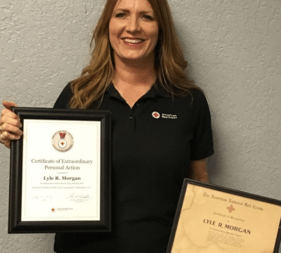 Ames Davis holding her grandfather's original Red Cross Lifesaving Award and his updated award.