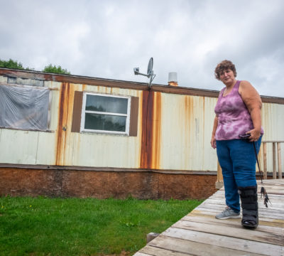 Margaret Phillips standing outside of her damaged home.