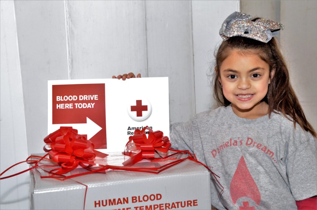 Daniela Ciriello standing next to a blood donation sign
