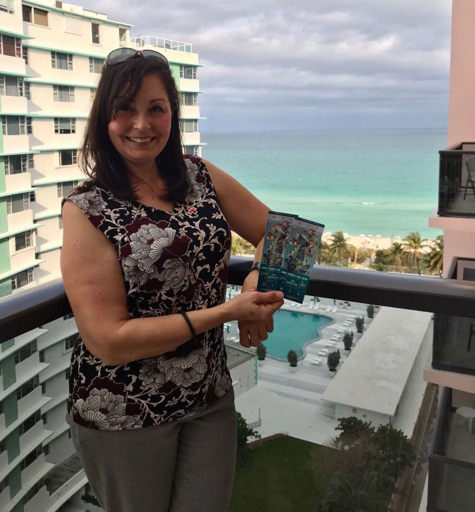Manolita standing on a balcony in Miami with her Super Bowl tickets. 
